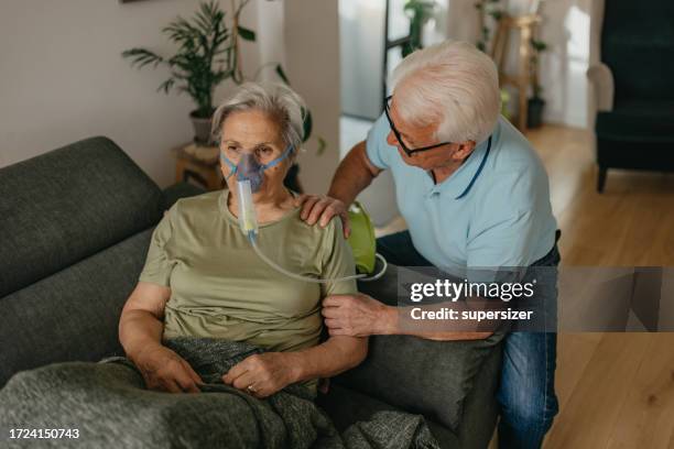 hombre mayor asistiendo a una mujer mayor durante el proceso de inhalación médica - oxígeno fenómeno natural fotografías e imágenes de stock