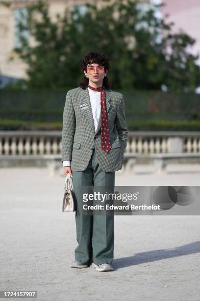 Loic Hornecker wears sunglasses, a red tie, a white top, a green oversized blazer jacket, green suit pants, shoes, outside Casablanca, during the...