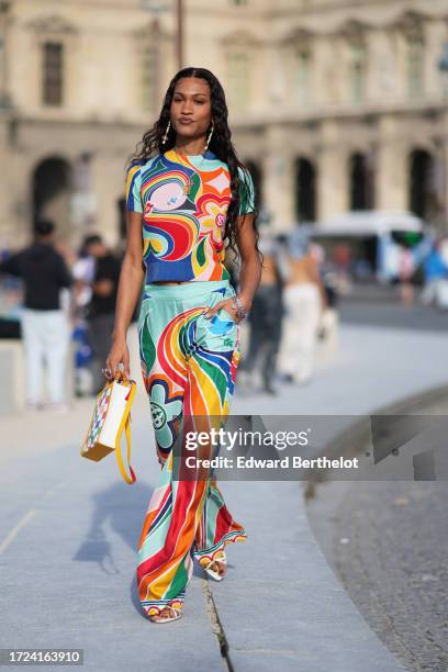 Guest wears, earrings, a multi color floral print t-shirt, matching flowing flared pants outside Casablanca, during the Womenswear Spring/Summer 2024...