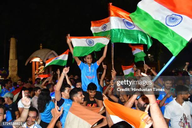 Supporters of the Indian cricket team wave national flags as they celebrate after winning the Cricket World Cup group stage match between India and...