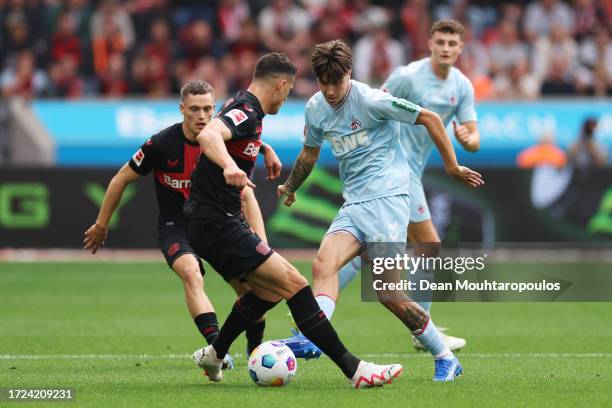 Denis Huseinbasic of 1.FC Köln is put under pressure by Patrik Schick and Florian Wirtz of Bayer Leverkusen during the Bundesliga match between Bayer...