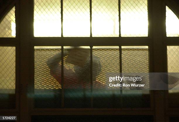 Detainee at the INS Building holds up a note and acknowledges protesters as they rally outside against the mass detentions and round-up of immigrants...