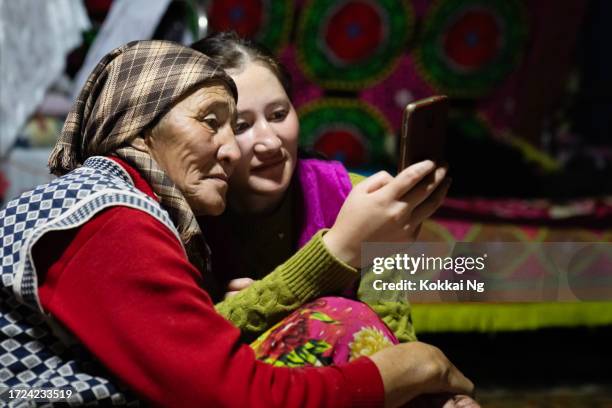 ethnische kasachische frauen telefonieren per videoanruf mit verwandten in ger, mongolei - zentralasien stock-fotos und bilder