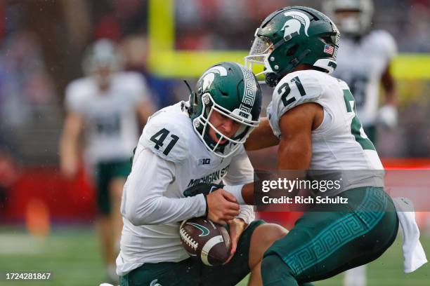 Derrick Harmon of the Michigan State Spartans is helped up by Dillon Tatum of the after recovering a fumble on a punt return by Shaquan Loyal of the...