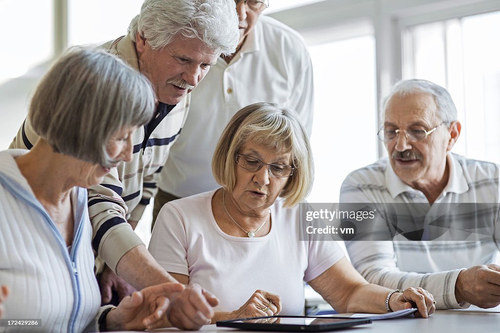 Group of seniors examine digital tablet