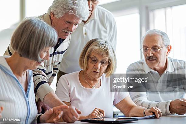 group of seniors examine digital tablet - online seminar stock pictures, royalty-free photos & images