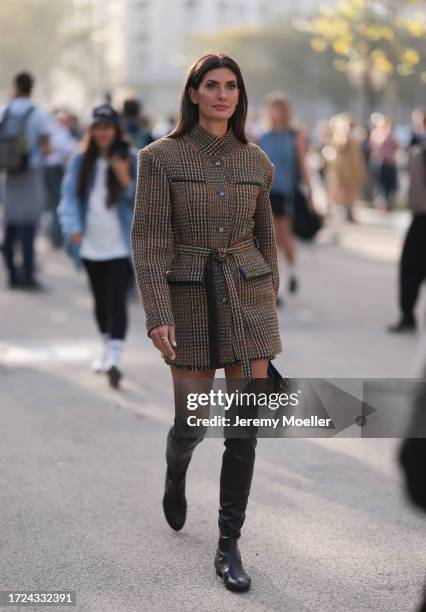 Fashion Week Guest is seen wearing a brown, orange plaid wool coat with belt and high collar, black leather overknees, plus a black beige handbag...