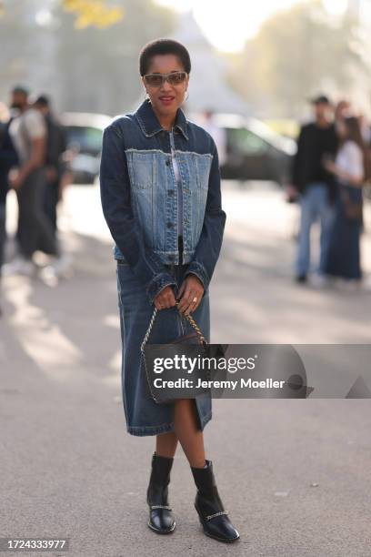 Tamu McPherson is seen wearing a denim jacket, a white Tshirt, a midi denim skirt with a slit, black leather boots with silver details, gray...