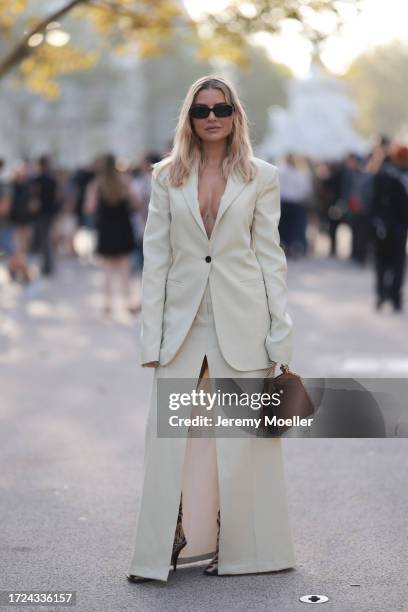 Veronica Ferraro is seen wearing a long white blazer with a maxi skirt in white and slit, a brown leather handbag and overknees in leo print with...