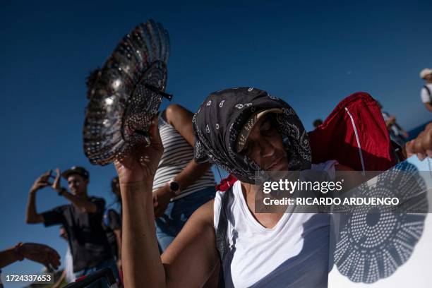 Woman uses a kitchen colander to cast the shadow of the sun on a white board during the annular solar eclipse in Old San Juan, Puerto Rico on October...