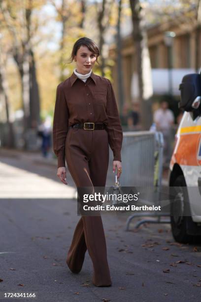 Mary Leest wears a turtleneck pullover, a brown jumpsuit, a belt, a white Fendi bag, outside Akris, during the Womenswear Spring/Summer 2024 as part...