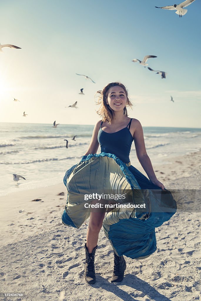 Girl in long dress on the beach with birds, sunset.