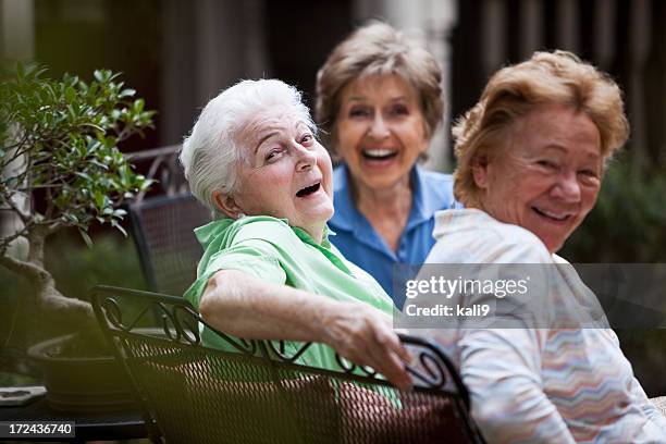 three elderly women laughing on patio - community centre stock pictures, royalty-free photos & images