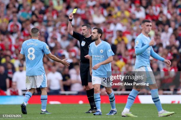 Match Referee Michael Oliver shows a yellow card to Mateo Kovacic of Manchester City during the Premier League match between Arsenal FC and...