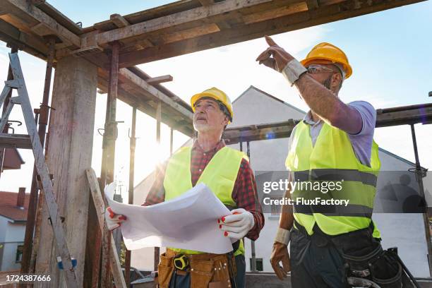 caucasian engineer and building contractor having an meeting about project on a construction site - real estate developer stock pictures, royalty-free photos & images