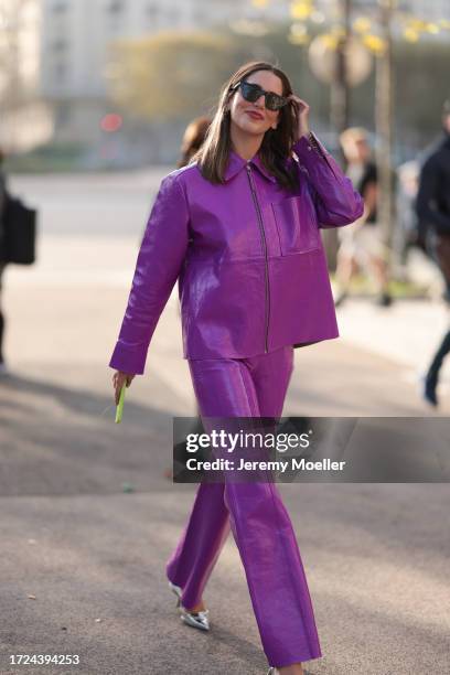 Fashion Week Guest is seen wearing a purple leather jacket with pocket and purple leather pants, silver Prada high heels and black sunglasses during...