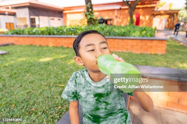 asian young boy drinking using tumbler - malay archipelago stock pictures, royalty-free photos & images