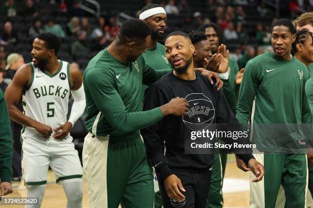 Thanasis Antetokounmpo speaks with Damian Lillard of the Milwaukee Bucks prior to a preseason game against the Chicago Bulls at Fiserv Forum on...