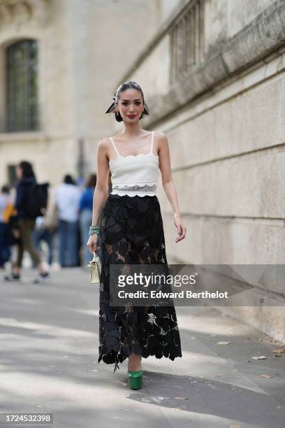 Heart Evangelista wears a white tank top with embroidery, a black lace mesh floral embroidered long skirt, a Hermes bag, green platform shoes,...