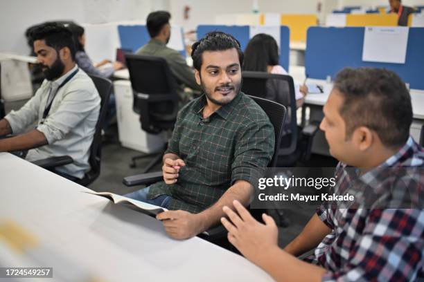 co-workers engaged in productive conversation during work at office - india office stock pictures, royalty-free photos & images