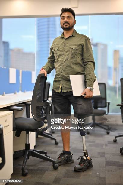 portrait of a mid-adult man with a prosthetic leg in an office cubicle - disabilitycollection ストックフォトと画像