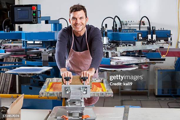 man operating screen printing equipment - silk screen stock pictures, royalty-free photos & images