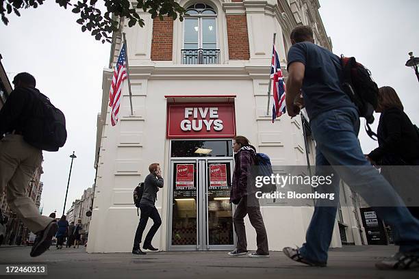 Pedestrians walk past the first U.K. Outlet of U.S. Burger restaurant chain Five Guys in London, U.K., on Tuesday, July 2, 2013. Five Guys, which is...