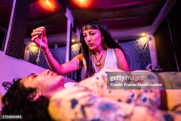 therapist using pendulum during therapy session on a spa - hypnosis stock pictures, royalty-free photos & images