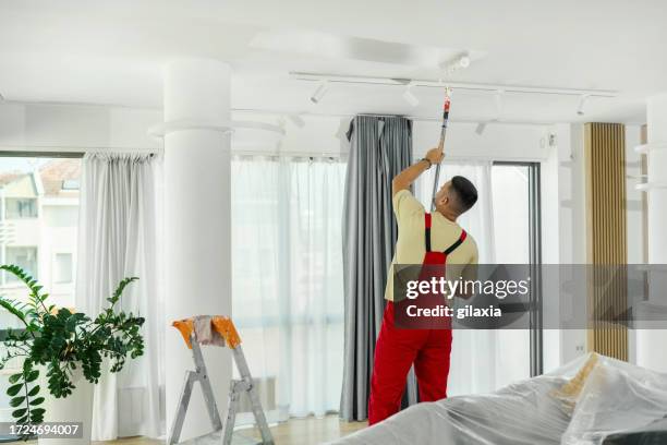 handyman painting walls at his home. - painting ceiling stock pictures, royalty-free photos & images
