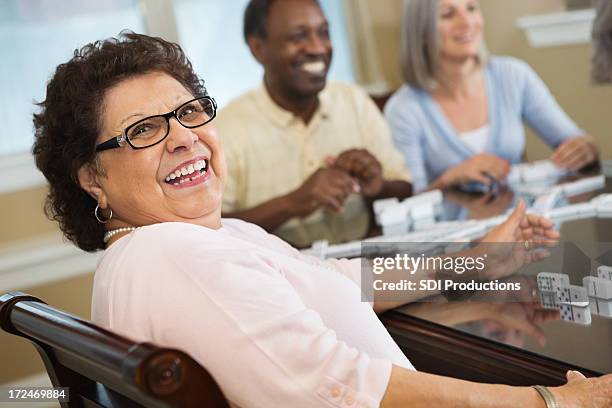 happy hispanic senior woman playing dominoes with friends - dominoes stock pictures, royalty-free photos & images