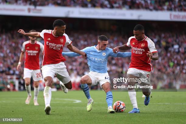 Phil Foden of Manchester City holds off from William Saliba and Gabriel Jesus of Arsenal during the Premier League match between Arsenal FC and...