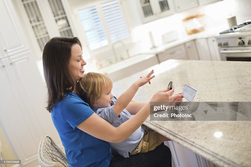 Boy With Mother Depositing Check Through Mobile Phone