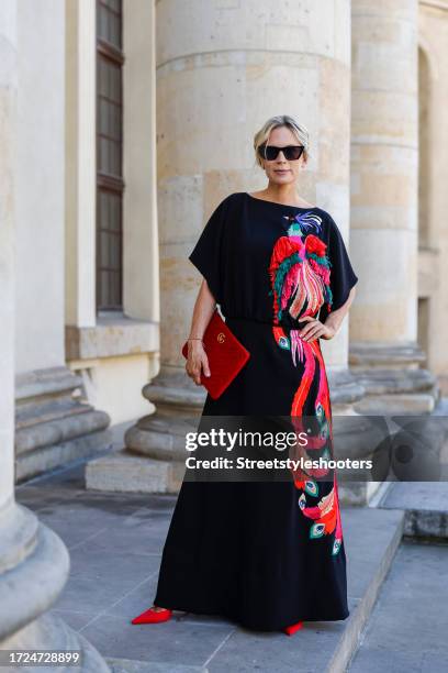 Influencer Tamara von Nayhauss, wearing a black long dress with a big red bird print by Maison Common, red pumps by Zara, sunglasses by Zara and a...