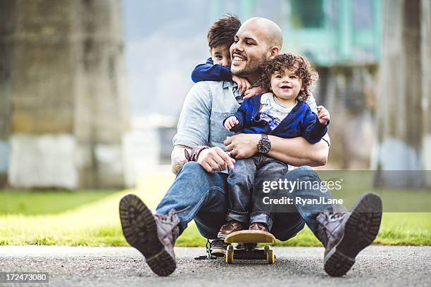 dad on a skateboard at a park with two sons - father and son park stock pictures, royalty-free photos & images