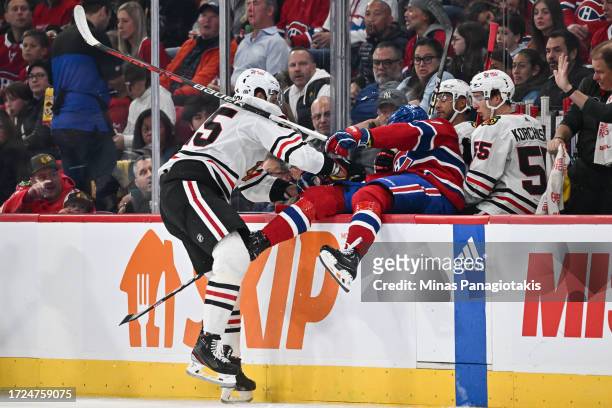Jarred Tinordi of the Chicago Blackhawks pushes Kirby Dach of the Montreal Canadiens into the Blackhawks bench during the first period at the Bell...