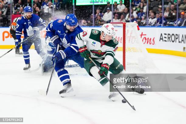 Marco Rossi of the Minnesota Wild battles for the puck against Mark Giordano of the Toronto Maple Leafs during the first period at the Scotiabank...