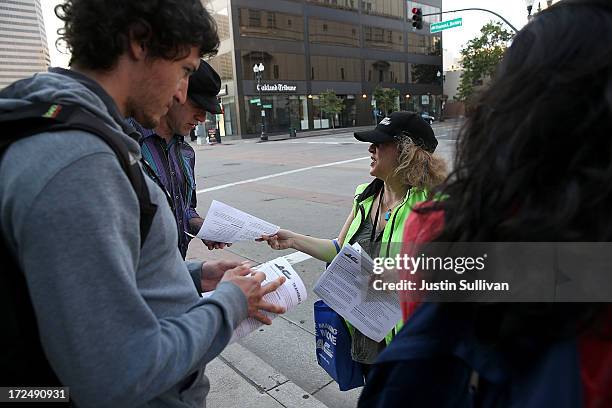 An Alameda-Contra Costa Transit worker passes out bus information to commuters as they wait in line to board an AC Transit bus on July 2, 2013 in...