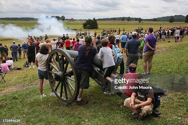 Tourists watch Confederate Civil War re-enactors fire a cannon on the 150th anniversary of the historic Battle of Gettysburg on July 2, 2013 in...