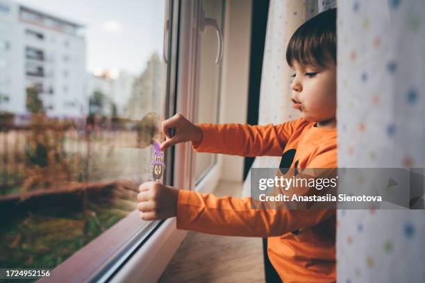 little boy decorating window by stickers - use by label bildbanksfoton och bilder