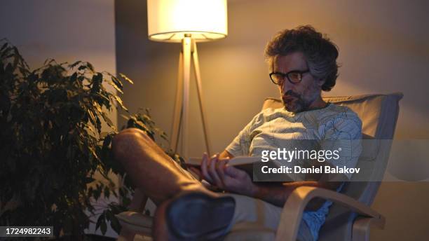 mature man reading a book late at night. relax at home. - lamp imagens e fotografias de stock