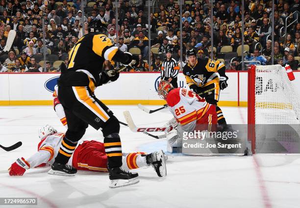 Evgeni Malkin of the Pittsburgh Penguins score past Jacob Markstrom of the Calgary Flames in the third period at PPG PAINTS Arena on October 14, 2023...