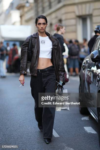 Model wears a white Loewe top, a brown leather jacket, a belt, black jeans, pointed leather shoes, outside Victoria Beckham, during the Womenswear...