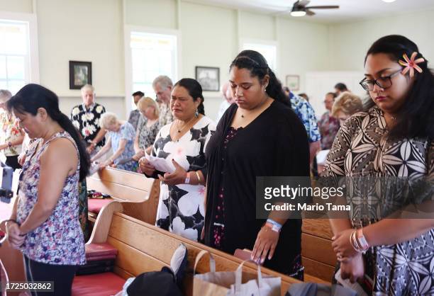 Members of Lahaina United Methodist Church, which was destroyed in the August 8th wildfire, pray during Sunday services at their temporary location...
