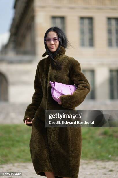 Yoyo Cao wears sunglasses, a green khaki fluffy long coat, a pink bag, outside Loewe, during the Womenswear Spring/Summer 2024 as part of Paris...