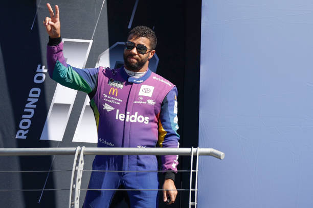 Bubba Wallace, driver of the Leidos Toyota, waves to fans as he walks onstage during driver intros prior to the NASCAR Cup Series Bank of America...