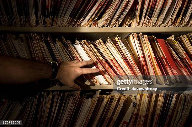 a man in front of a bookshelf of medical records - stealing data stock pictures, royalty-free photos & images