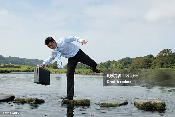 man losing his balance on a rock near a pond  - stumble stock pictures, royalty-free photos & images