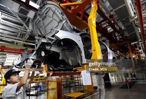 Employees work on the assembly line of the Citroen C-Elysee at the third plant of Dongfeng Peugeot Citroen Automobile Co., Ltd on July 2, 2013 in...