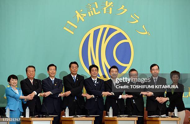 Japanese Prime Minister and ruling Liberal Democratic Party leader Shinzo Abe shakes hands with Democratic Party of Japan leader Banri Kaieda and...