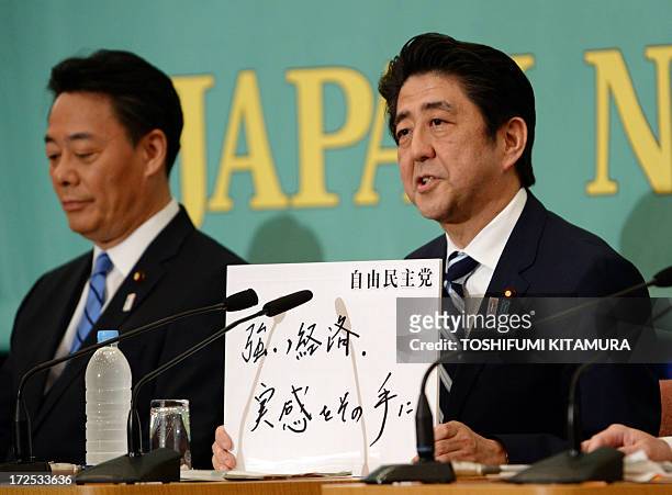 Japanese Prime Minister and ruling Liberal Democratic Party leader Shinzo Abe displays the slogan for the upcoming election reading "Strong economy....